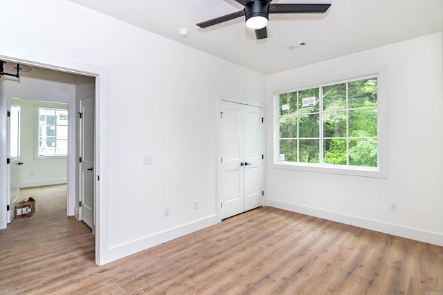 unfurnished bedroom with light wood finished floors, baseboards, visible vents, and ceiling fan