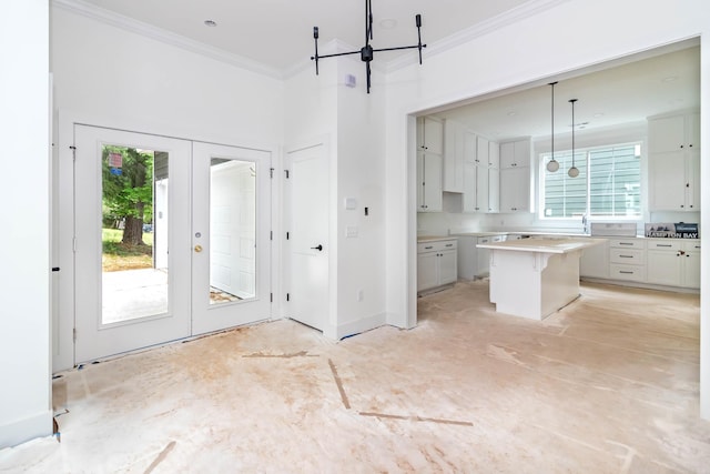 kitchen with a kitchen island, crown molding, french doors, white cabinetry, and pendant lighting