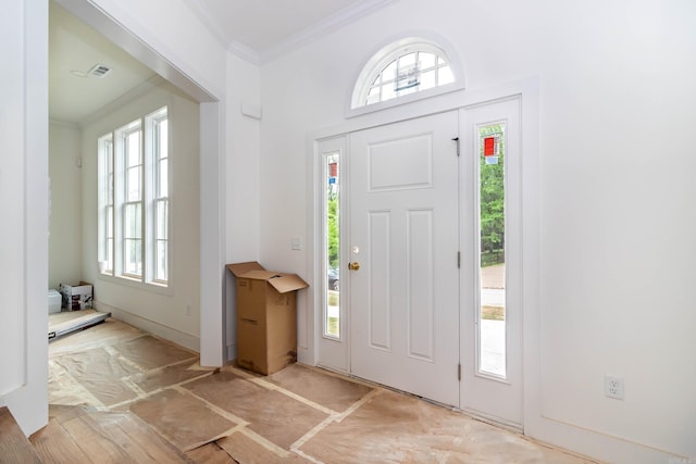 foyer entrance featuring visible vents and crown molding