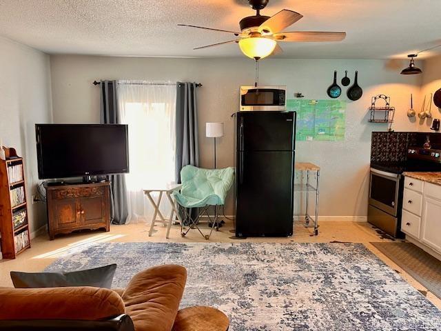 living area featuring ceiling fan, baseboards, and a textured ceiling