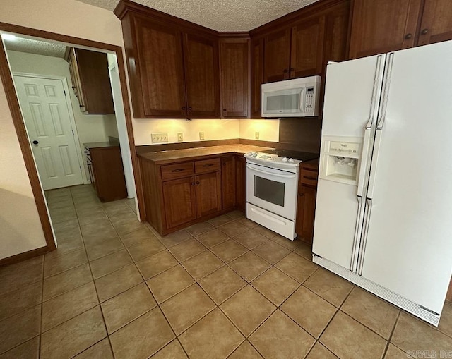 kitchen featuring light tile patterned floors, white appliances, and a textured ceiling