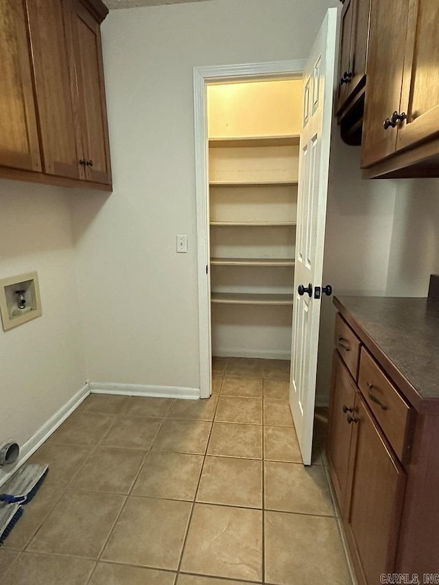 laundry room with light tile patterned flooring, hookup for a washing machine, cabinet space, and baseboards