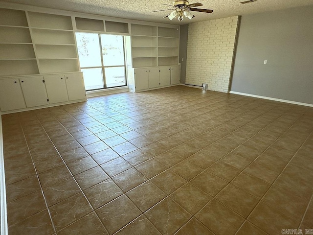 spare room with visible vents, built in shelves, a ceiling fan, and a textured ceiling