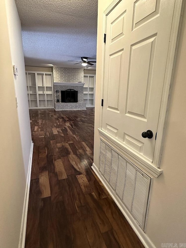 corridor featuring dark wood finished floors, a textured ceiling, and baseboards