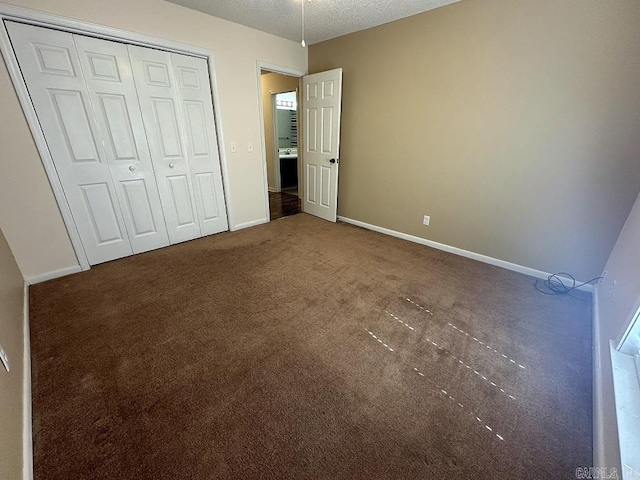 unfurnished bedroom featuring carpet, a closet, a textured ceiling, and baseboards