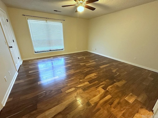 empty room featuring baseboards, visible vents, a ceiling fan, dark wood-type flooring, and a textured ceiling