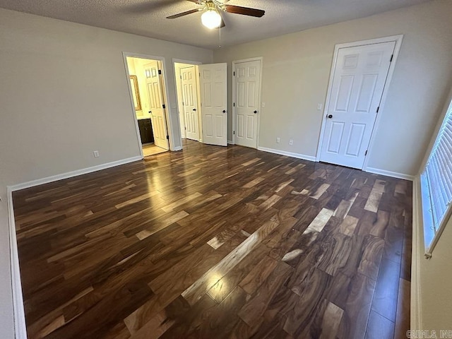 unfurnished bedroom featuring a textured ceiling, ceiling fan, ensuite bathroom, baseboards, and dark wood finished floors