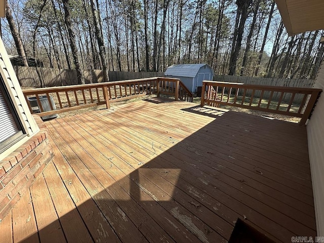 wooden terrace featuring an outbuilding, a shed, and a fenced backyard