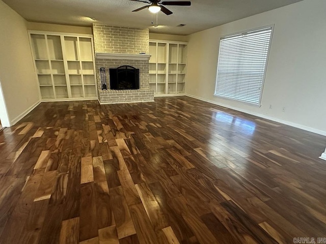 unfurnished living room with ceiling fan, dark wood-type flooring, a fireplace, and baseboards