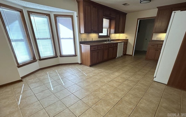 kitchen with white appliances, light tile patterned floors, baseboards, visible vents, and dark countertops