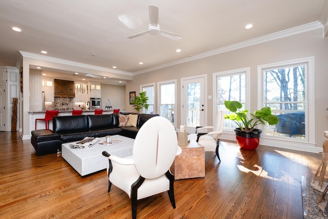 living area featuring a wealth of natural light, crown molding, recessed lighting, and wood finished floors