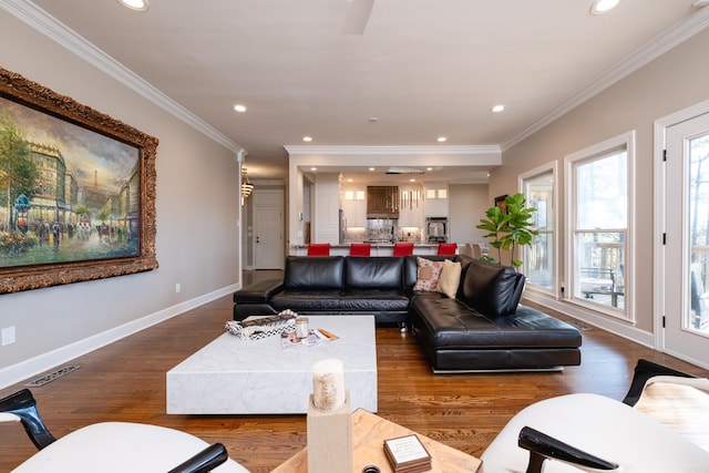 living room with ornamental molding, recessed lighting, wood finished floors, and baseboards