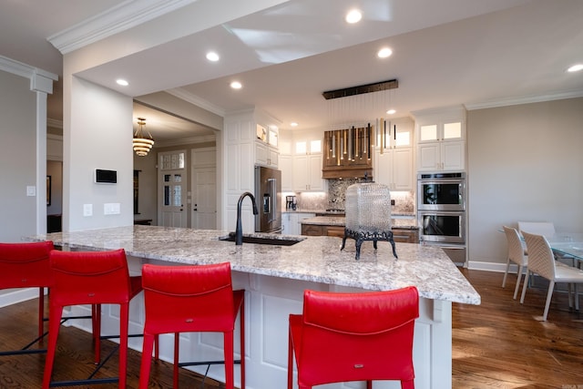 kitchen with decorative backsplash, appliances with stainless steel finishes, ornamental molding, dark wood-type flooring, and a sink