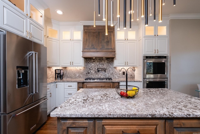 kitchen featuring appliances with stainless steel finishes, decorative backsplash, crown molding, and a center island