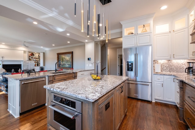 kitchen with stainless steel appliances, a sink, open floor plan, backsplash, and a center island