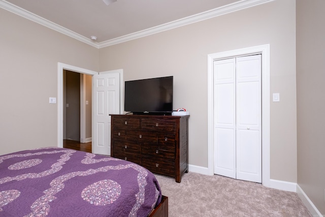 carpeted bedroom with a closet, crown molding, and baseboards