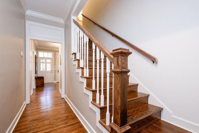 stairway featuring baseboards, crown molding, and wood finished floors