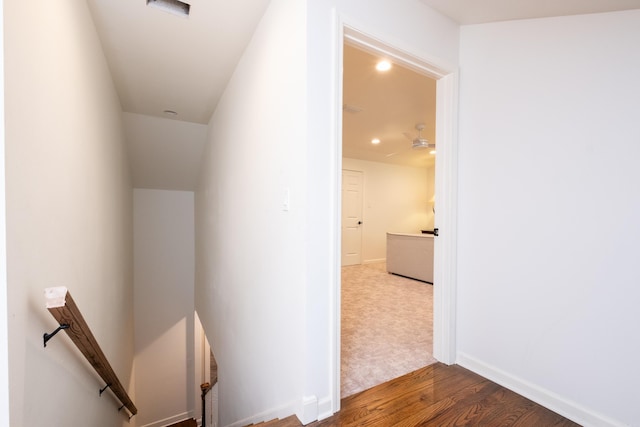 hall with wood finished floors, an upstairs landing, and baseboards