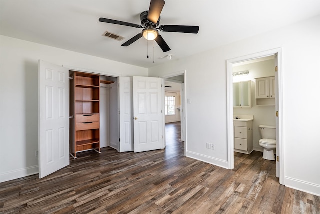 unfurnished bedroom with ensuite bath, baseboards, visible vents, and dark wood finished floors