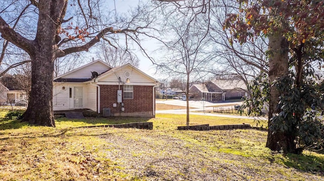 view of front of house featuring a front yard, central AC unit, and brick siding