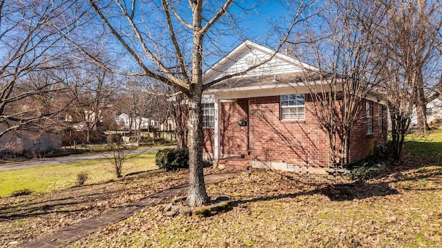 view of side of home featuring crawl space, a lawn, and brick siding