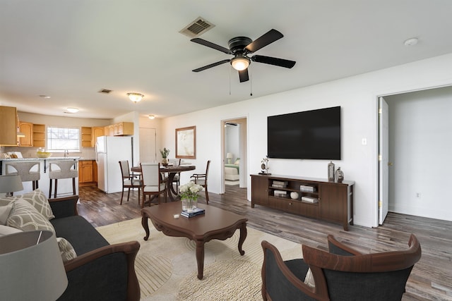 living area featuring a ceiling fan, baseboards, visible vents, and dark wood-style flooring