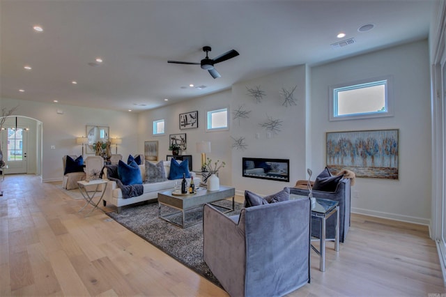 living room featuring arched walkways, recessed lighting, visible vents, light wood-type flooring, and baseboards