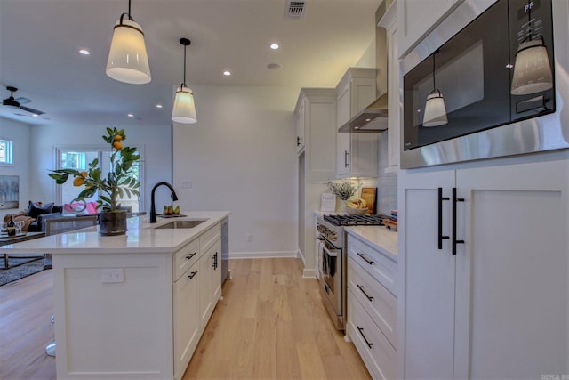 kitchen featuring stainless steel appliances, a sink, visible vents, light countertops, and wall chimney exhaust hood