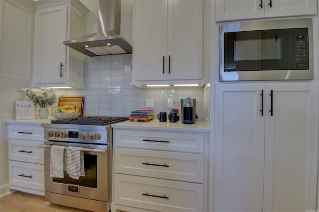 kitchen featuring tasteful backsplash, built in microwave, high end range, and wall chimney range hood