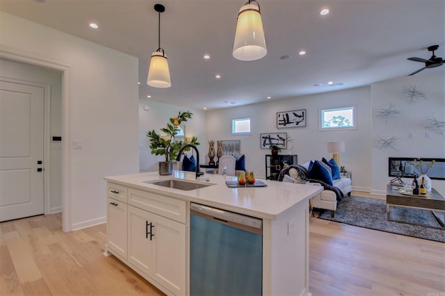 kitchen featuring light wood-style flooring, a sink, open floor plan, stainless steel dishwasher, and pendant lighting