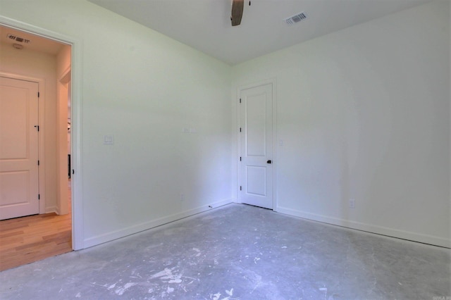 empty room featuring a ceiling fan, visible vents, concrete floors, and baseboards