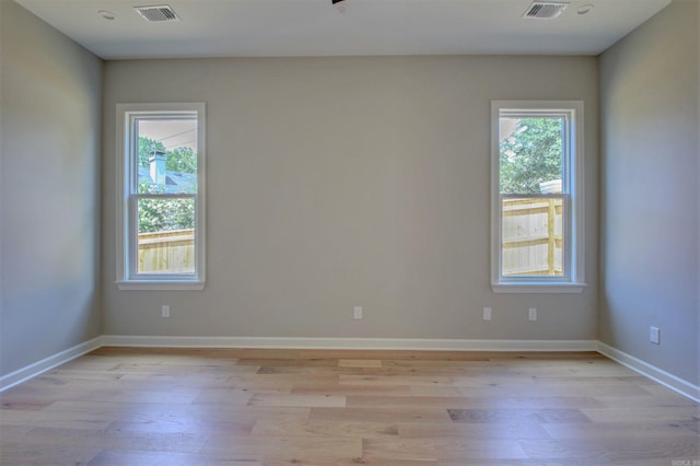 unfurnished room featuring light wood finished floors, baseboards, and visible vents