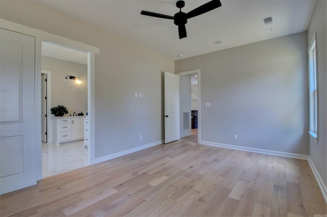 unfurnished bedroom featuring baseboards, ensuite bathroom, visible vents, and light wood-style floors