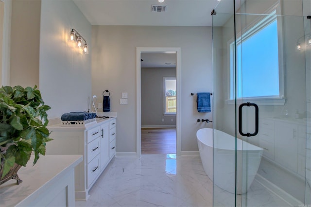 bathroom with marble finish floor, a soaking tub, visible vents, vanity, and baseboards