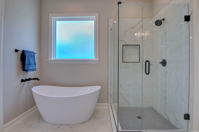 bathroom featuring a freestanding bath, marble finish floor, a marble finish shower, and baseboards