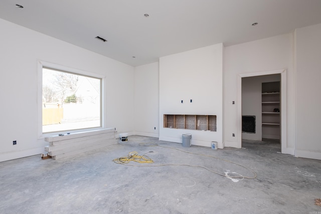 unfurnished living room featuring unfinished concrete flooring and baseboards