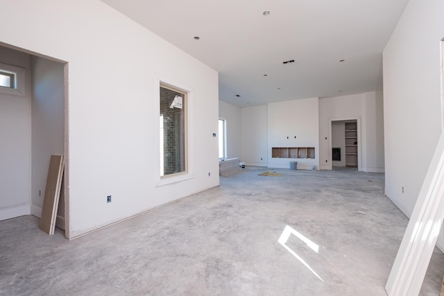 unfurnished living room with a healthy amount of sunlight and unfinished concrete floors