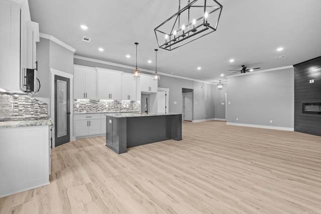 kitchen featuring a large fireplace, ceiling fan, white cabinets, and decorative backsplash