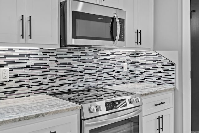 kitchen featuring light stone countertops, appliances with stainless steel finishes, white cabinets, and backsplash