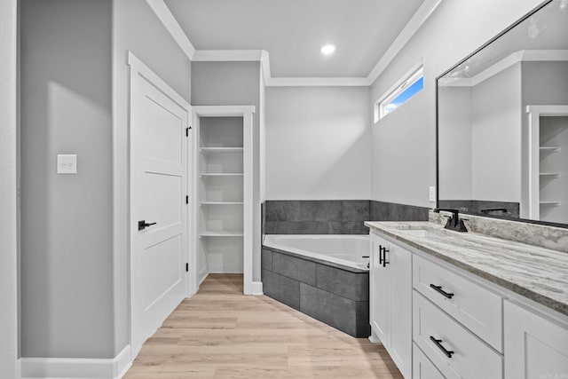 bathroom with vanity, wood finished floors, a bath, and crown molding