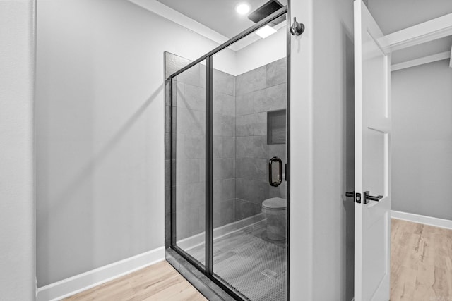 bathroom featuring toilet, a shower stall, baseboards, and wood finished floors