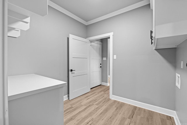 clothes washing area featuring light wood finished floors, baseboards, and ornamental molding