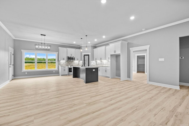 kitchen with a kitchen island with sink, stainless steel appliances, open floor plan, light countertops, and decorative backsplash