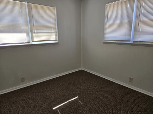 unfurnished room featuring dark colored carpet and baseboards