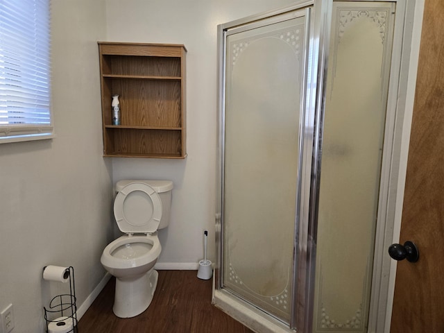 bathroom with a stall shower, toilet, baseboards, and wood finished floors