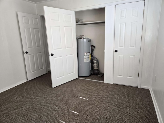 interior space with water heater, dark colored carpet, a closet, and baseboards