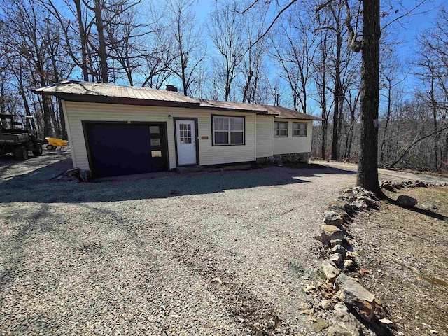 exterior space with driveway, a chimney, and metal roof