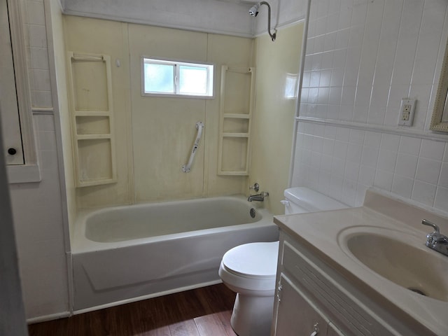 bathroom featuring toilet, wood finished floors, vanity, tile walls, and shower / washtub combination