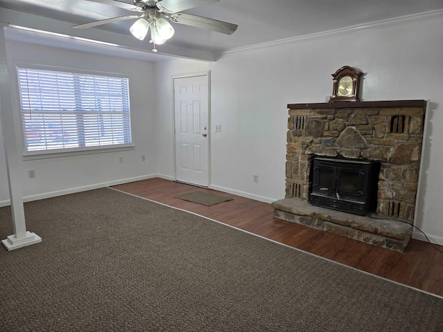 unfurnished living room with ornamental molding, a ceiling fan, a stone fireplace, wood finished floors, and baseboards