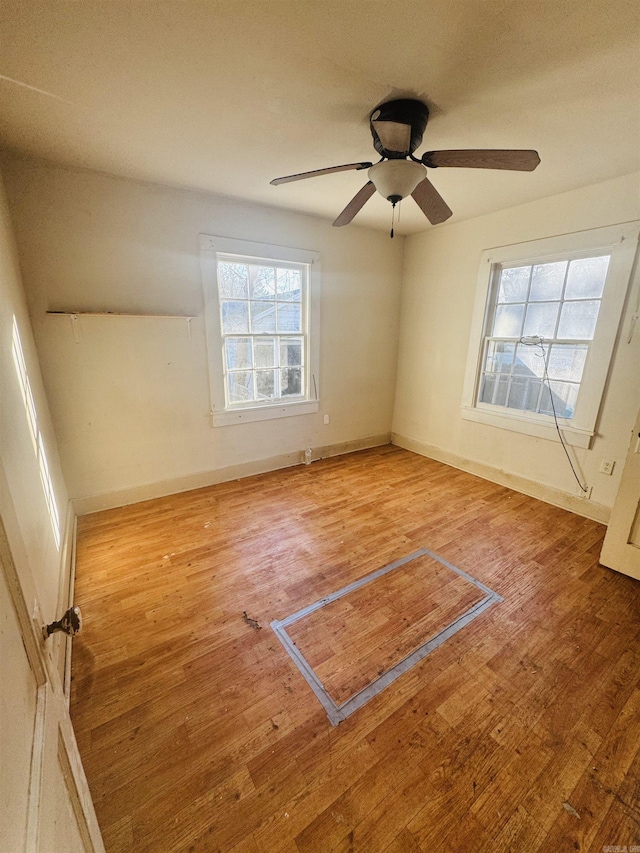 spare room featuring a ceiling fan, wood-type flooring, and baseboards